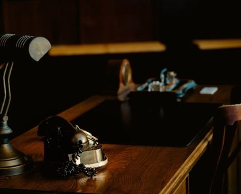 Bureau de travail sobre et raffiné, documents financiers ou juridiques posés sur un bureau en bois sombre ou pierre naturelle, lumière naturelle latérale tamisée, atmosphère de réflexion et de décision stratégique — aucun visage identifiable ou en arrière-plan flou, ancrage possible dans un environnement architectural marocain moderne ou un bureau premium nord-africain.