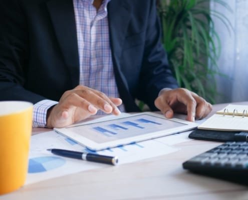 Un dirigeant senior seul ou en petit comité, en situation de réflexion face à des documents financiers ou un écran d'analyse. Ambiance sobre, lumière naturelle ou tamisée, environnement bureau moderne. L'image doit transmettre le doute sérieux, pas l'échec — la pensée stratégique, pas la détresse.